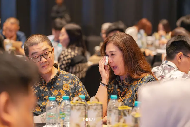 Seorang ibu menyeka air mata dengan tisu sementara pria di sebelahnya menatapnya